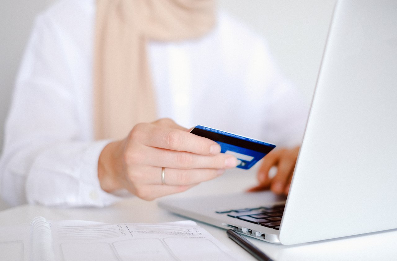 Person holding credit card in front of computer