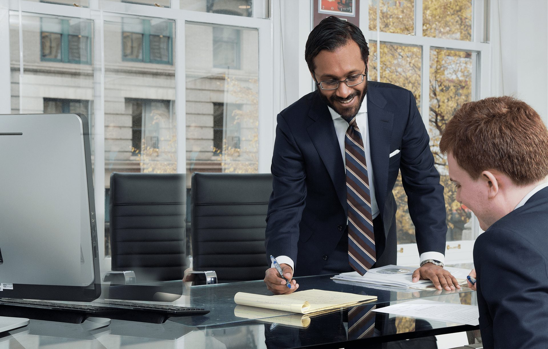 Lawyer standing next to a table with another lawyer sitting