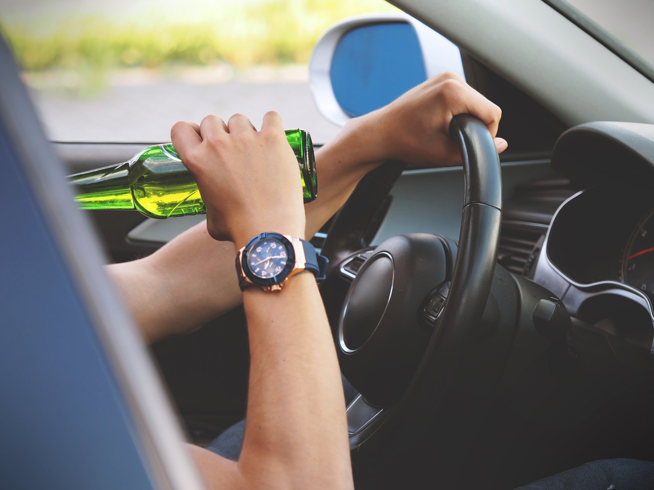 Person drinking a beer while driving a car