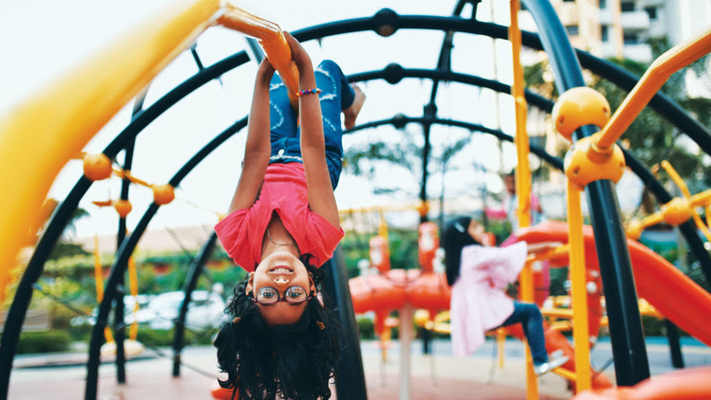 child hanging upside down on a playground