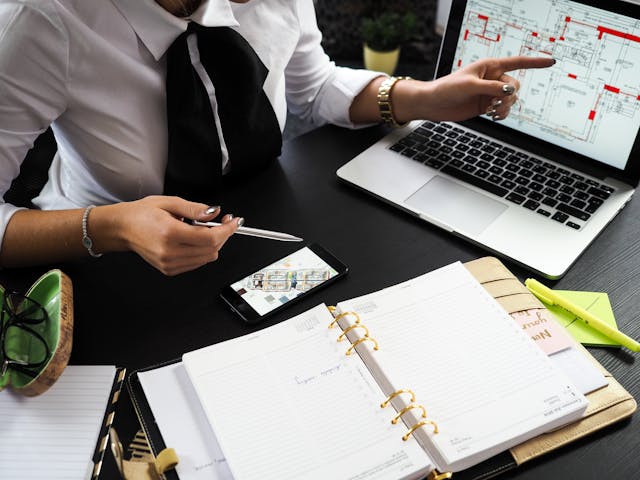 a lawyer working with documents and a laptop with the plans of an estate on her desk